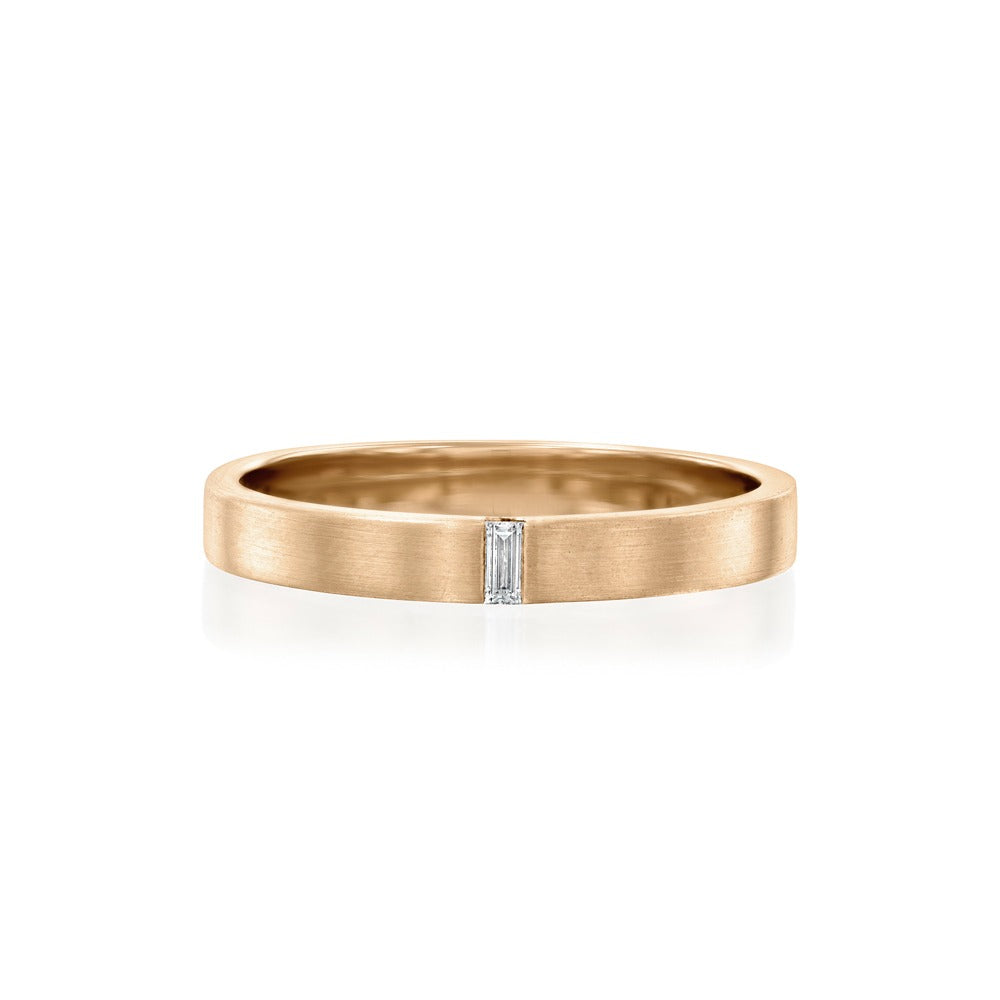 A flat gold ring for men and women set with a delicate, natural, sunken baguette diamond.